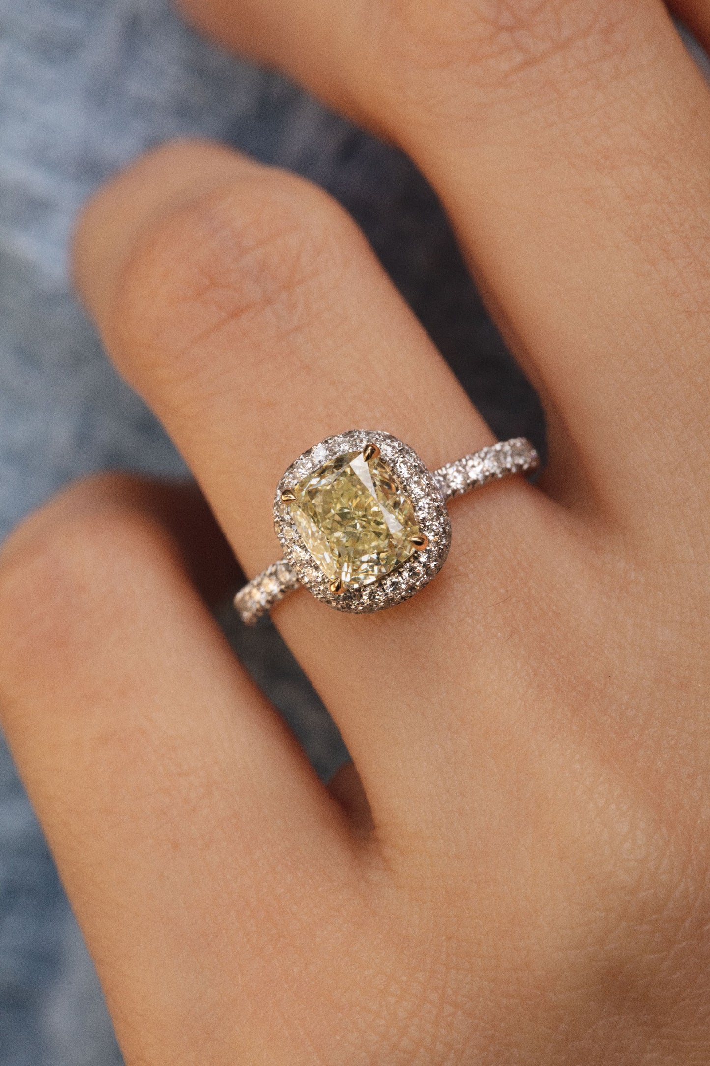 Photo zoomé sur la main de la femme. La monture est pavée entièrement de diamants blancs d'une pureté éblouissante qui contraste avec le jaune chaleureux de la pierre centrale jaune.