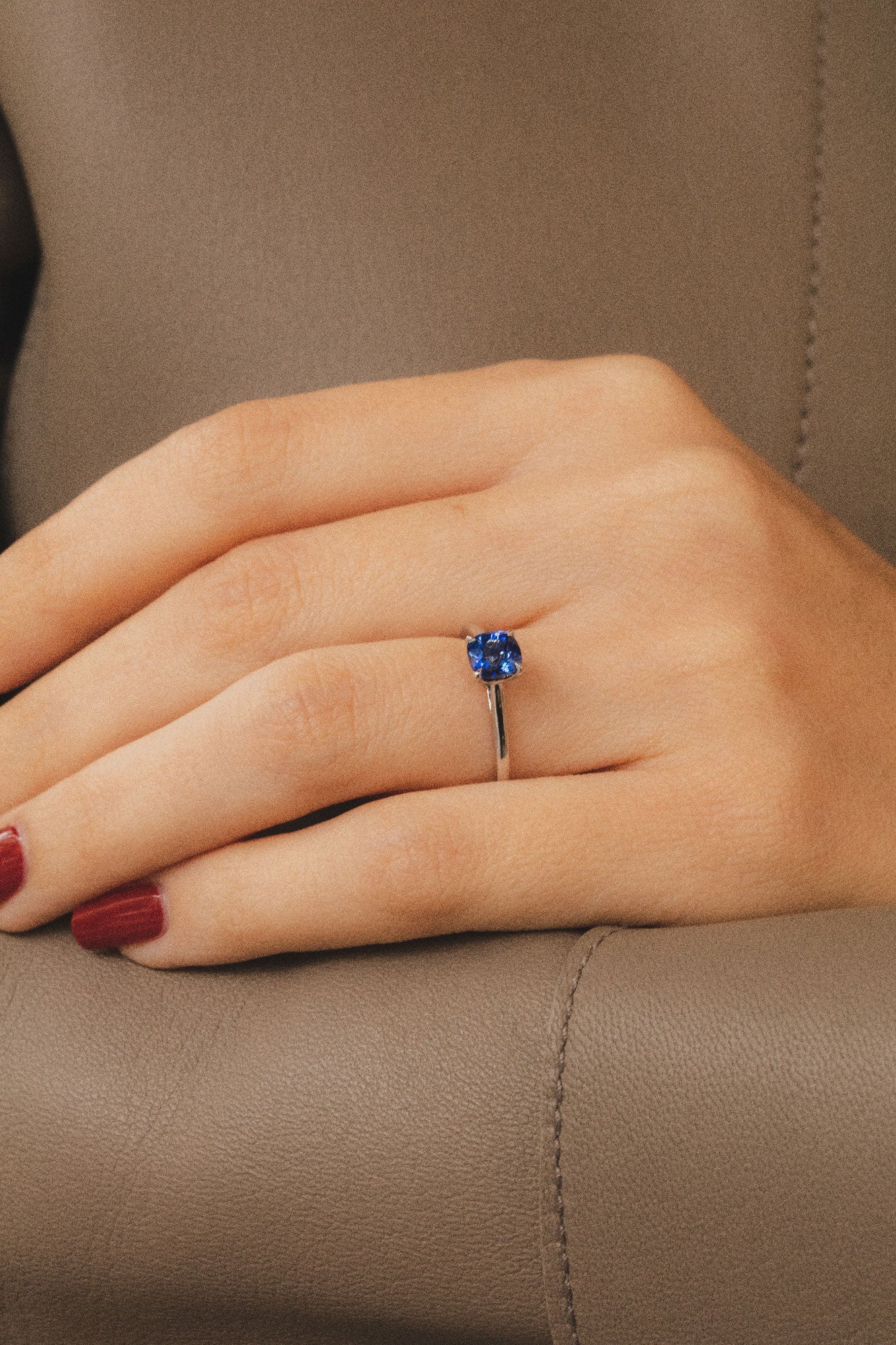 Photo zoomé sur une main portant une élégante bague en saphir bleu. Le design épuré de l'anneau sublime la beauté naturelle de la pierre centrale sertie en 4 griffes.