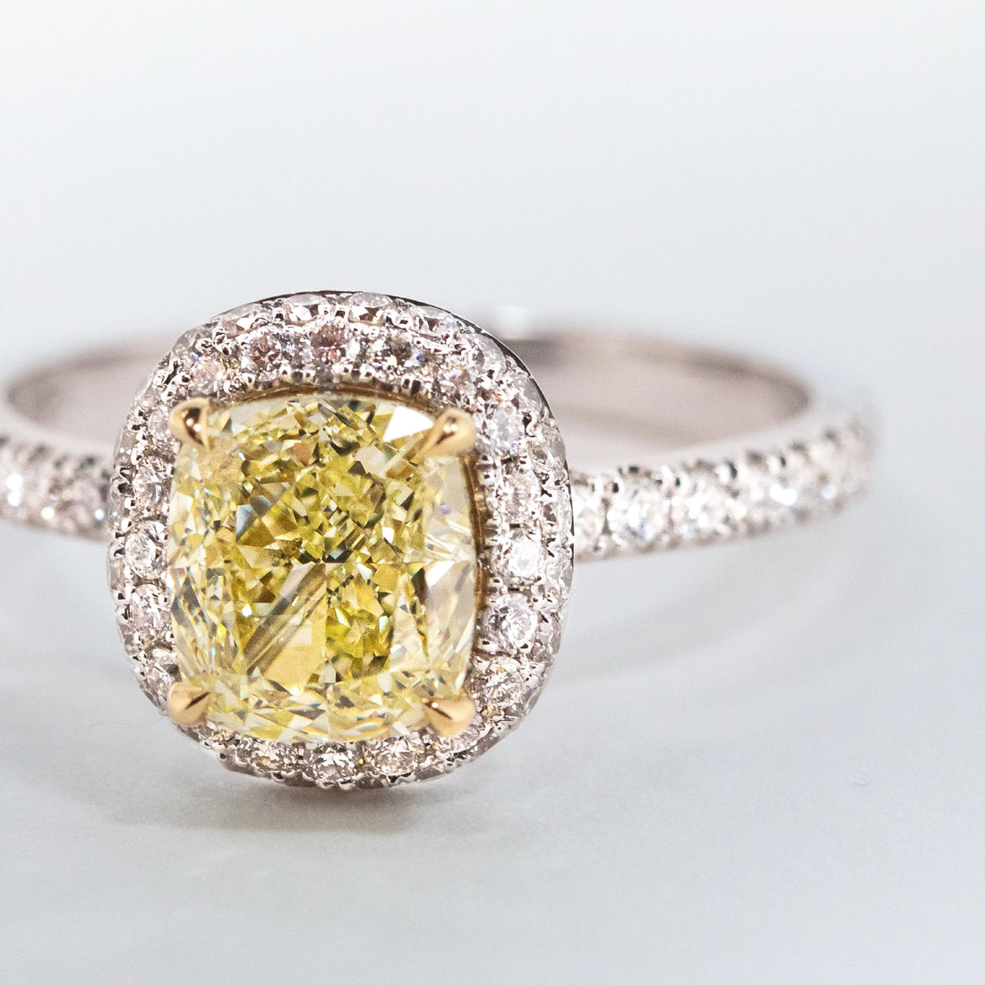 Bague à pierre jaune taille coussin entourée d'un halo pavé