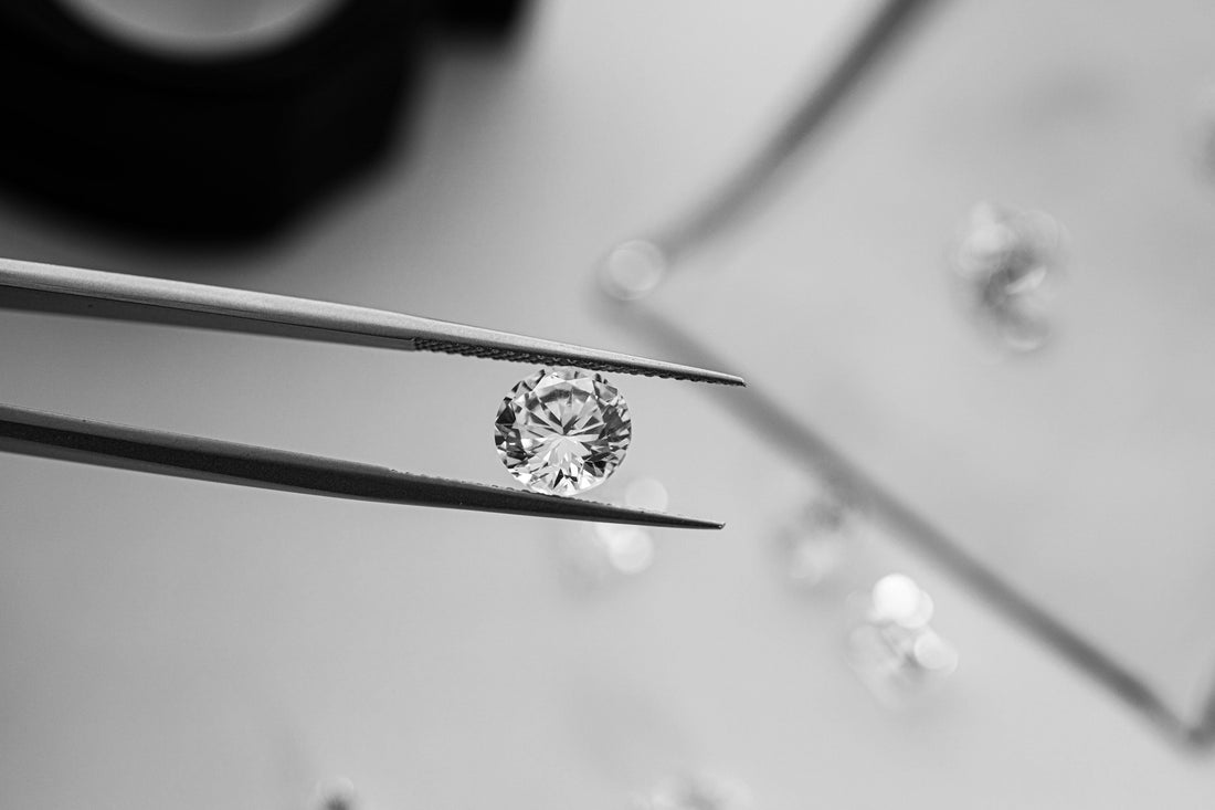 Diamant taille ronde tenu à la pince, entouré de pierres non serties