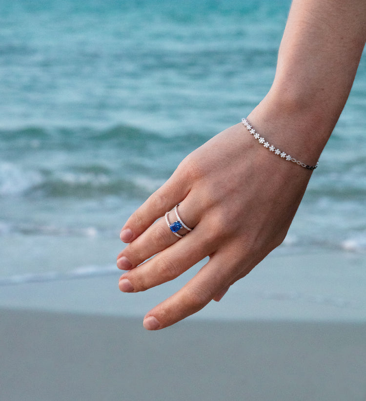 Photo portée d'une femme portant à son doigt le modèle Gentiane en or blanc, saphir bleu et diamants.