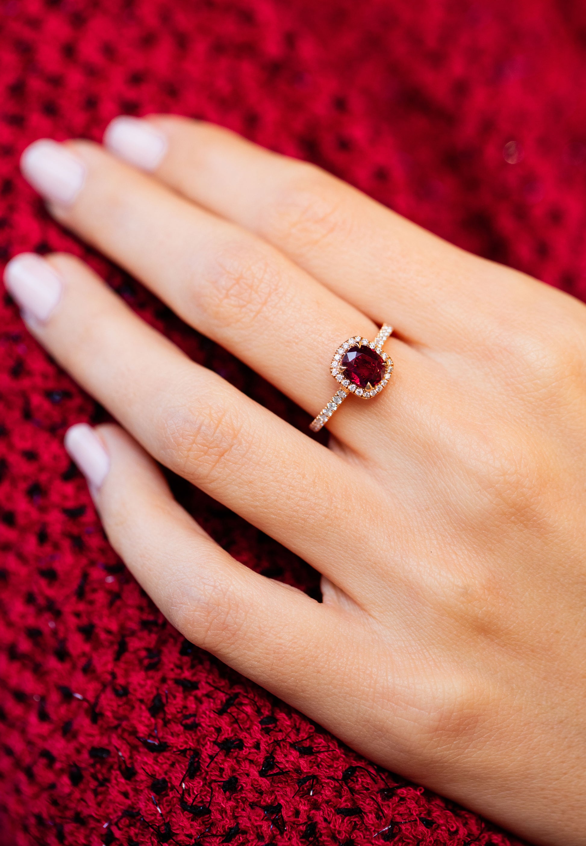 Main d'une femme portant le solitaire Camélia en rubis et or rose 18 carats