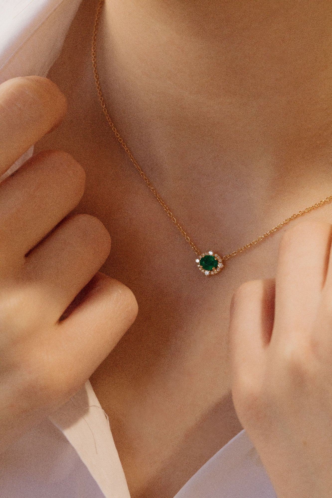 Photo porté d'un collier en émeraude vert dont l'éclat est souligné par un halo de diamants scintillants.