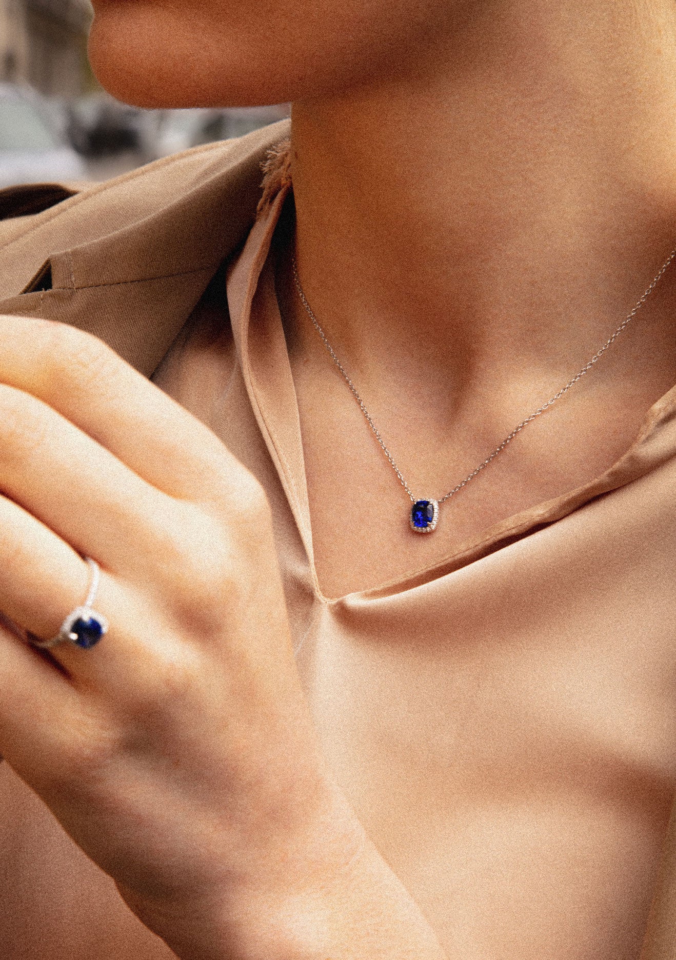 Photo d'une femme portant un collier et d'une bague en saphir bleu dans un design assortie pour une allure glamour.